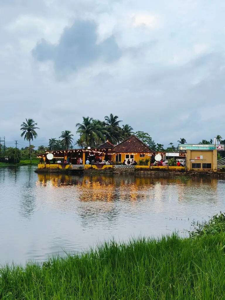Waterfront restaurant with palm trees reflecting on the water at dusk